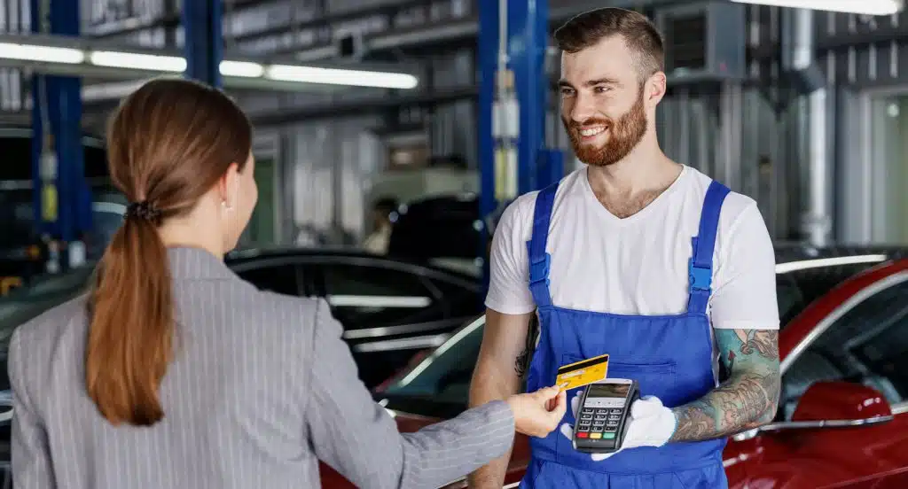 Frau bezahlt mit einer EC-Karte den Mechaniker in der Werkstatt