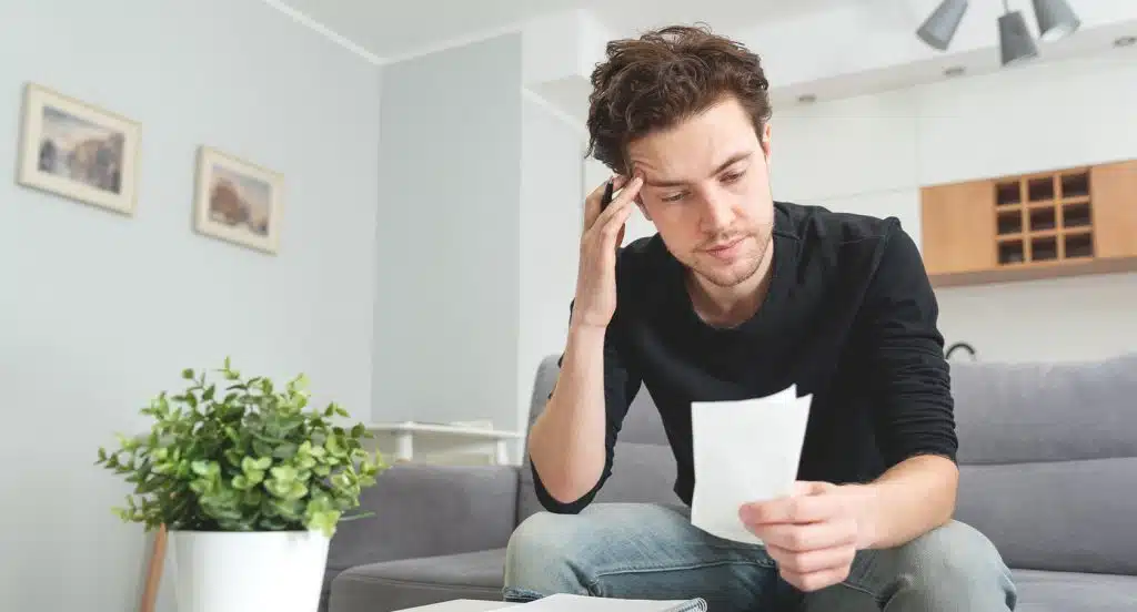 Mann sitzt auf einem Sofa und liest ein Dokument