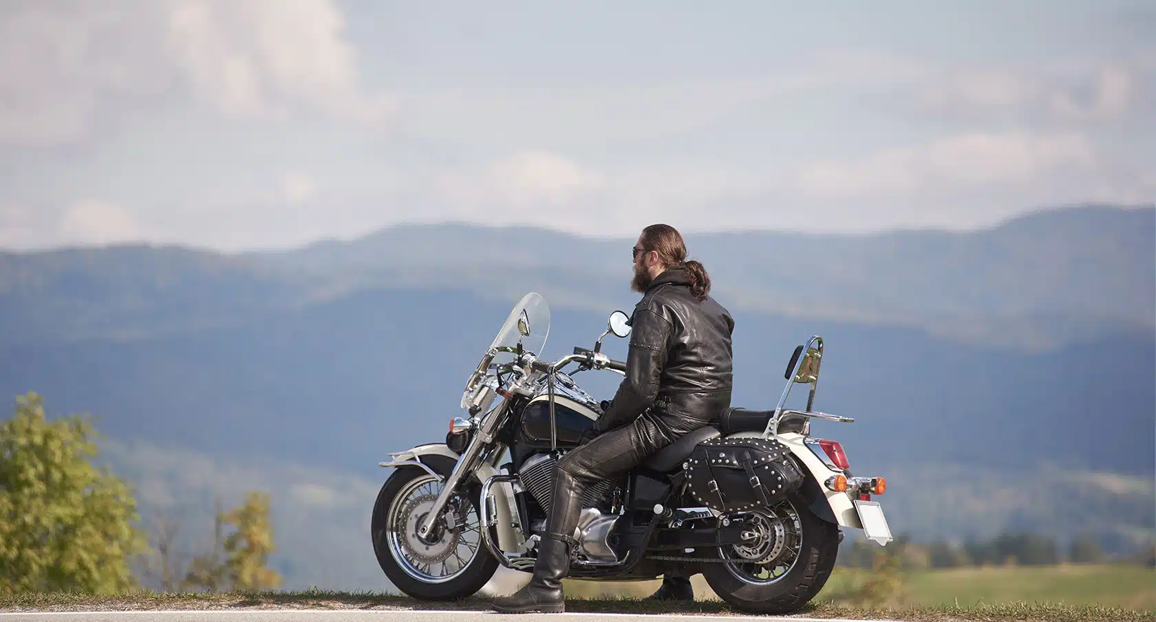 Biker sitzt auf einem schweren Motorrad vor einem Bergpanorama