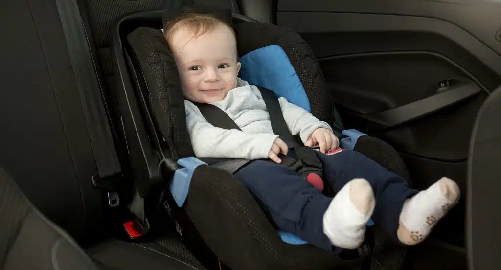 Baby sitzt in einer Babyschale auf dem Rücksitz eines Autos