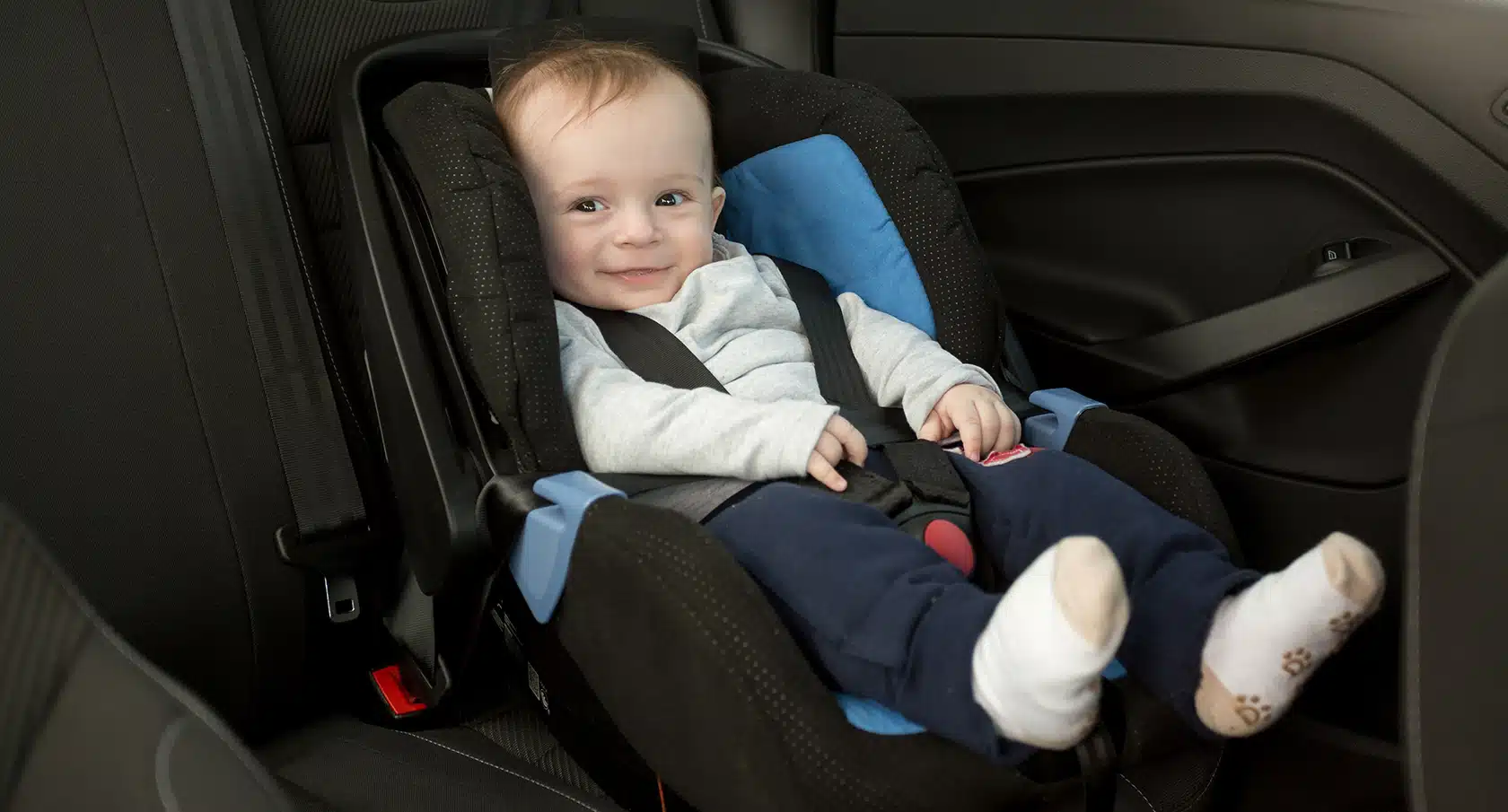 Baby sitzt in einer Babyschale auf dem Rücksitz eines Autos