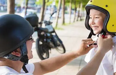 Vater macht Kind seinen Motorradhelm zu