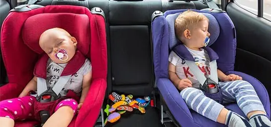 Zwei schlafende Kinder angeschnallt in ihren Kindersetzen im Auto
