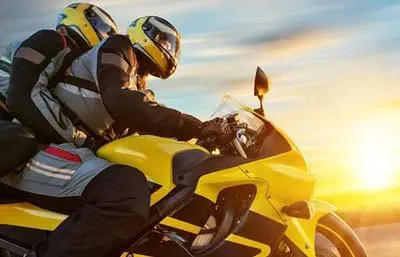 Motorradfahrer mit Beifahrer auf einem gelben Motorrad