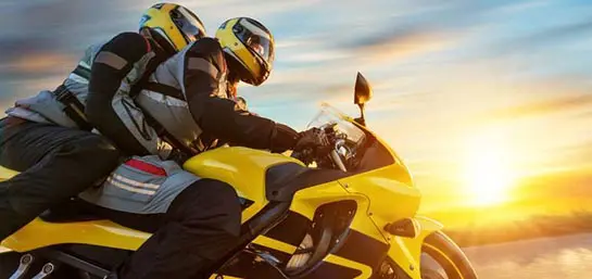 Motorradfahrer mit Beifahrer auf einem gelben Motorrad