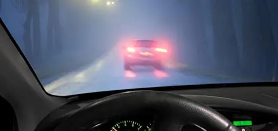 Rote Rücklichter eines Autos bei schlechter Sicht