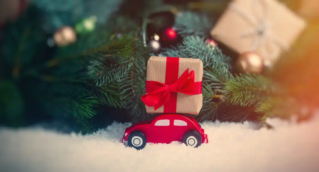 Spielzeugauto und verpacktes Geschenk unter einem weihnachtlich geschmückten Tannenbaum