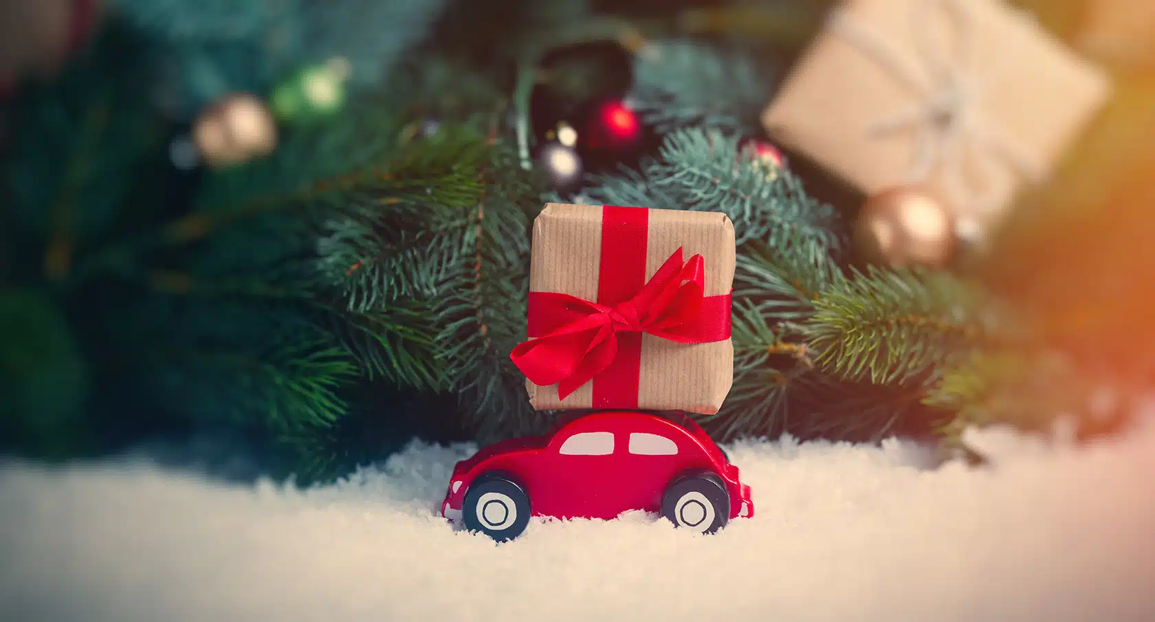 Spielzeugauto und verpacktes Geschenk unter einem weihnachtlich geschmückten Tannenbaum